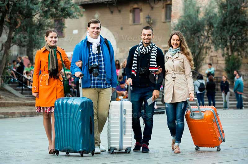 Travellers Baggage Sightseeing smiling. Two friends with Baggage. A couple of Tourists are Walking with Luggage left Side view. A couple of Tourists are Walking with Luggage Side view.